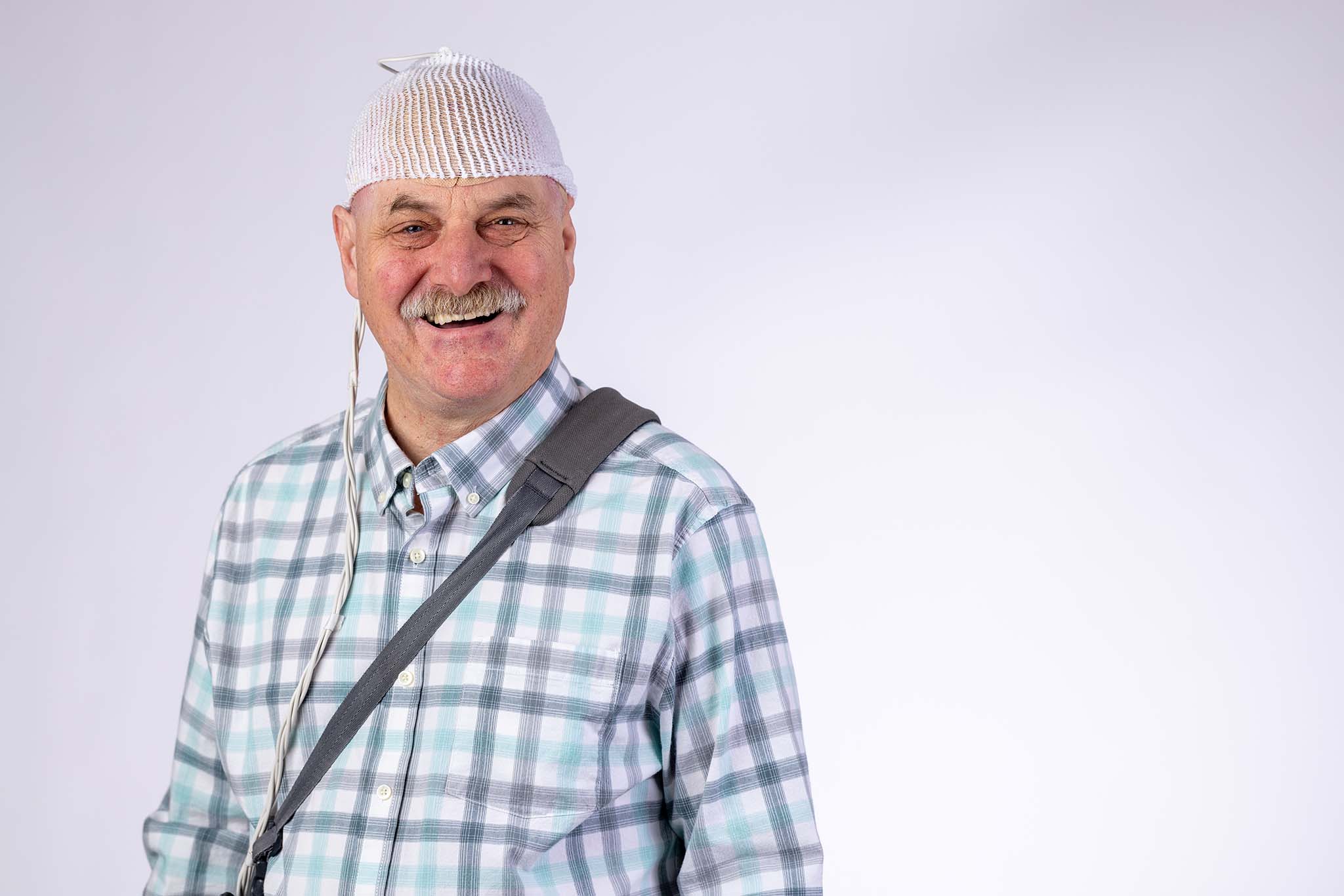 Scott smiles, wearing Optune Gio over his shoulder with the convertible bag.