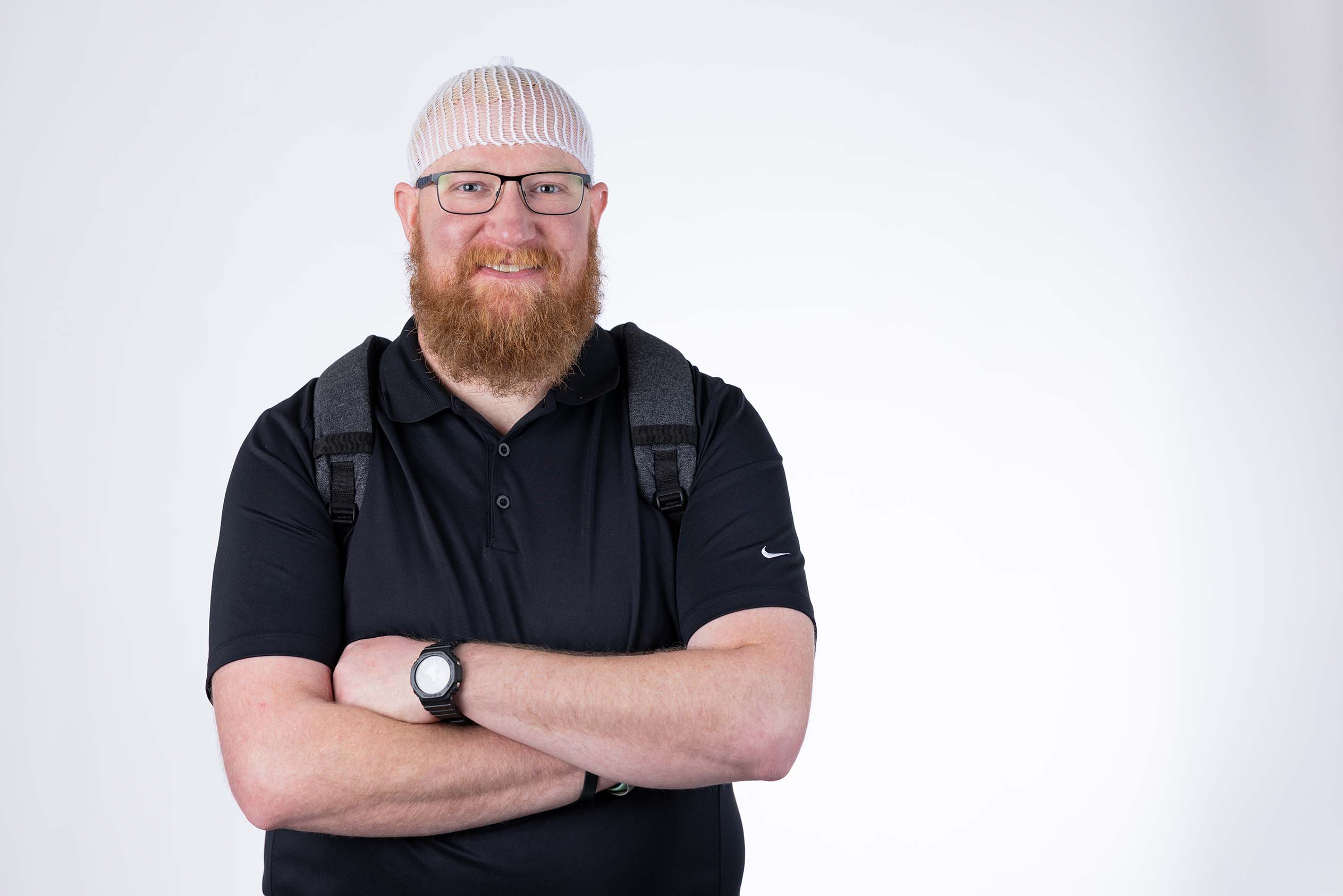 Taylor smiling with his arms crossed, wearing the Optune Gio arrays and backpack.