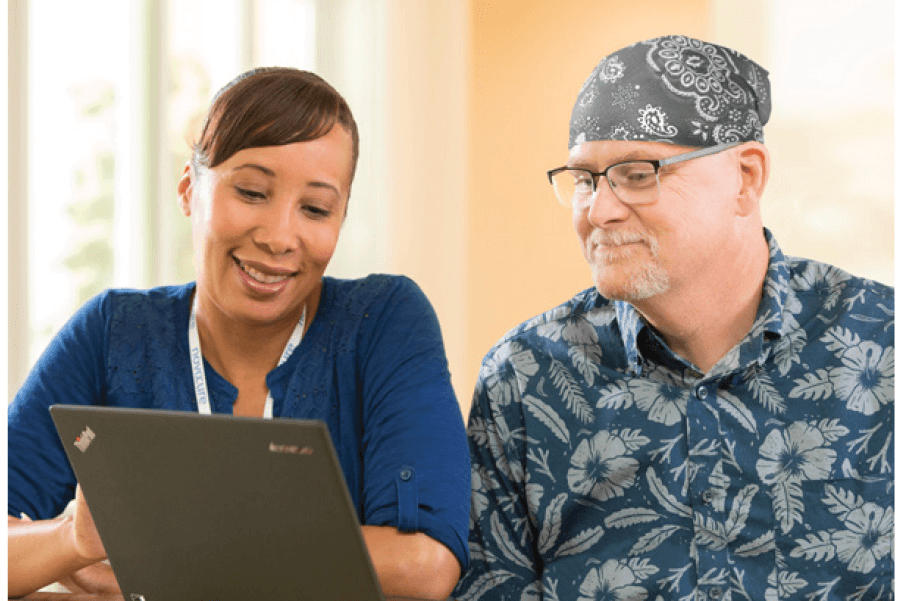 Erica assisting Steve with a laptop, highlighting supportive care and guidance.